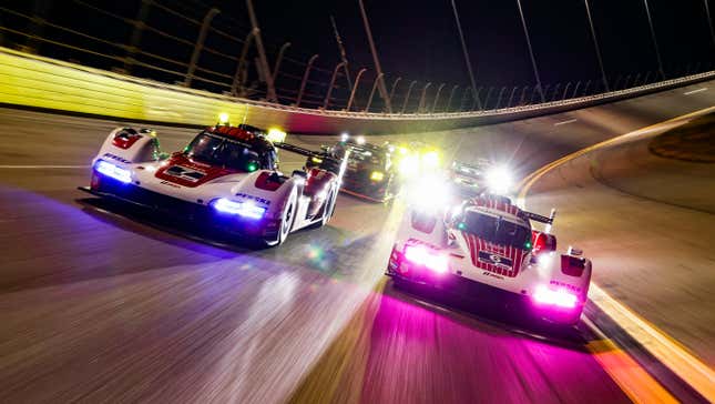 Porsche’s #6 and #7 963 GTP hypercar under the lights at Daytona International Speedway.