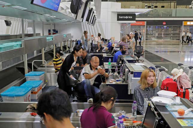 Stranded travelers sit in the check-in counters at Hong Kong International Airport, Aug. 12, 2019.