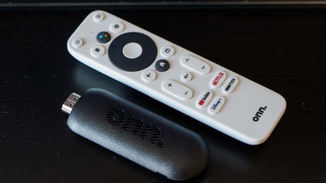 A photo of the Onn FHD Streaming Stick laying next to the Onn remote