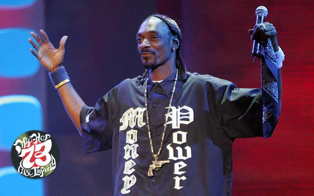 Snoop Dog stands on a stage with a microphone wearing a shirt that says Money Power
