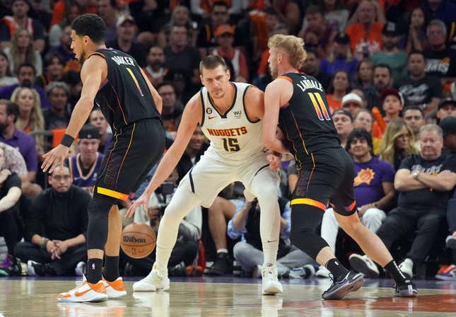 May 11, 2023; Phoenix, Arizona, USA; Denver Nuggets center Nikola Jokic (15) dribbles against Phoenix Suns guard Devin Booker (1) and Phoenix Suns center Jock Landale (11) during the first half of game six of the 2023 NBA playoffs at Footprint Center.