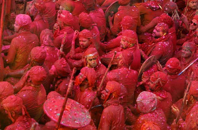 Men daubed in colours take part in Lathmar Holi celebrations.