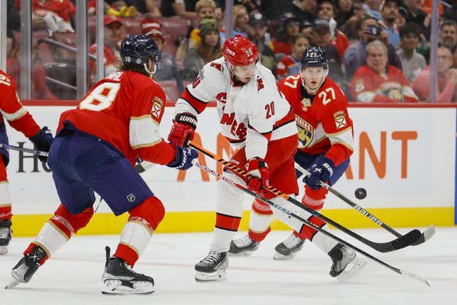 Apr 13, 2023; Sunrise, Florida, USA; Carolina Hurricanes center Sebastian Aho (20) controls the puck against Florida Panthers defenseman Marc Staal (18) and center Eetu Luostarinen (27) during the first period at FLA Live Arena.