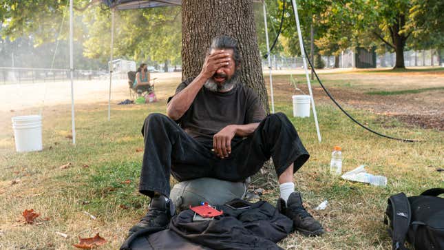 An unhoused man who asked to not be named tries to stay cool near a misting station in Lents Park during an extreme heat wave on Aug. 13, 2021 in Portland, Oregon.
