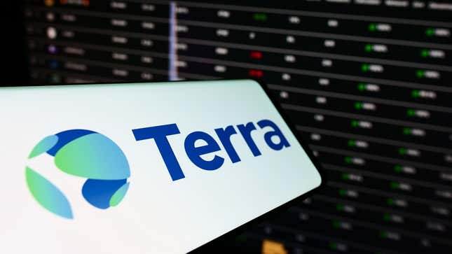 A phone with the Terra logo is shown against a backdrop of a screen showing market numbers.