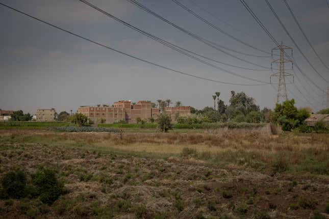 Power lines and an apartment building are visible behind a farm.