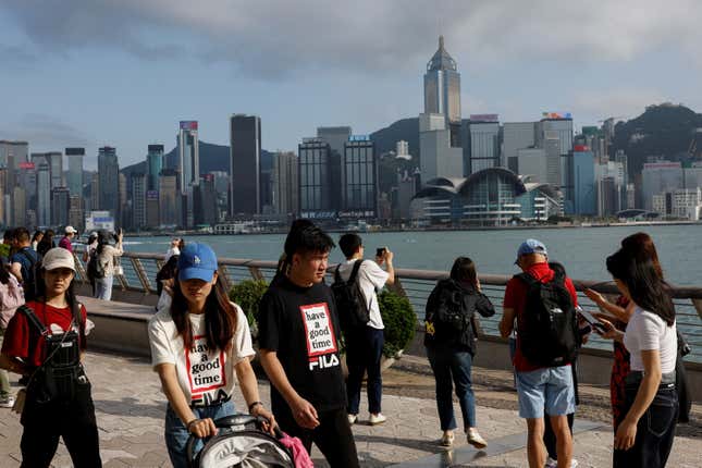 Mainland Chinese tourists walking in front of the Hong Kong skyline