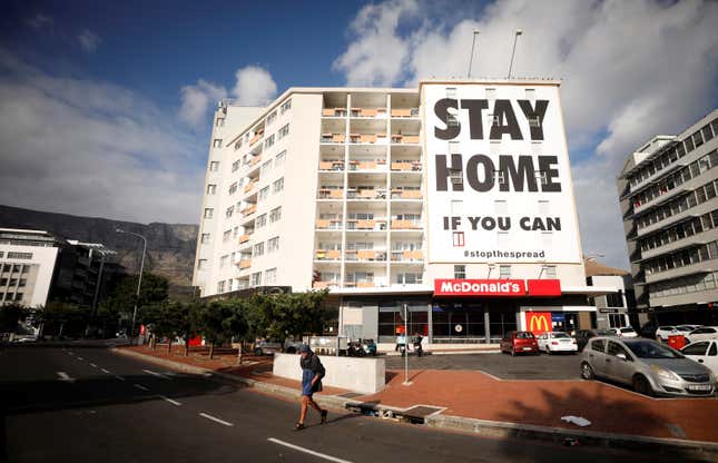 A man walks past a poster covering the side of a building ahead of a 21 day lockdown aimed at limiting the spread of coronavirus disease (COVID-19), in Cape Town, South Africa, Mar. 26, 2020.