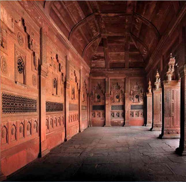 Jahangiri Mahal: A sequence of interconnected chambers, some embellished with plaster walls, leads to the riverside court of the Jahangiri Mahal, that was built between 1565 and 1569, in Fatehpur Sikri. It is defined by apartments on three sides, that on the west presents a triple-bayed, double-height entrance framed by slender stone columns that imitate timber originals. These features contrast with the arched recesses at either side and with the arched portals flanked by similarly-shaped recesses leading to the apartments on the north and south. A small octagonal pool set into the middle of the court is fed by a narrow water channel. The eastern perimeter of the court consists of a line of jalis (latticed screen) that permit views across the river. The walls (as seen from below) are adorned with polychrome panels set between octagonal towers with chhatris, as on the frontal facade of the pala.