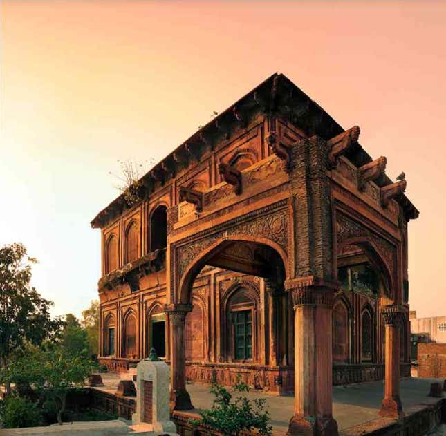 Shah Pir’s tomb: In between the Yamuna and Ganga, some 55 km northeast of Delhi, is Meerut, a city that rose to prominence under Akbar. The principal Mughal monument here is the mausoleum of a local saintly figure, known simply as Shah Pir, said to be a spiritual teacher of Jahangir. Though the patronage of the tomb is credited to Nur Jahan, the building was never completed, leaving the saint’s grave exposed to the sky. The dome-less, red sandstone structure is superbly finished, with well-articulated arched recesses on both its exterior and interior walls. The recesses are filled with diverse, jaali-like geometric patterns in intricately worked shallow relief, realised as perforated windows at both levels in the middle of each side. The tomb is raised on a terrace and was intended to be surrounded by a colonnade, but only a corner portion of this was finished.