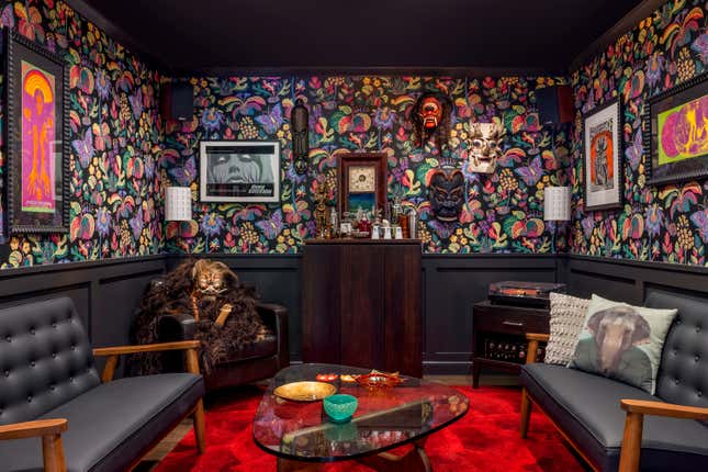 This photo provided by Clara Jung of Banner Day Interiors in San Francisco shows a cozy den with a vintage wood bar, a sprawl-worthy crimson rug, and Schumacher’s Exotic Butterfly wallpaper. (Vivian Johnson/Banner Day Interiors via AP)
