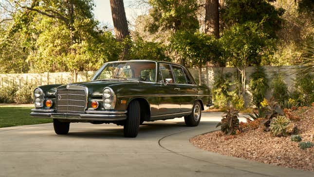 A green 1970 Mercedes sedan is parked on a curved driveway