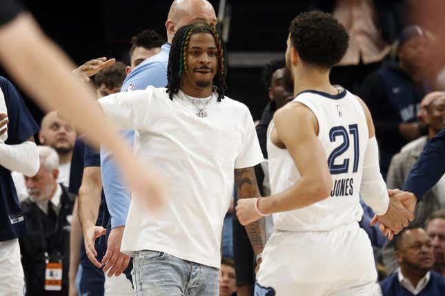 Mar 20, 2023; Memphis, Tennessee, USA; Memphis Grizzlies guard Ja Morant (left) reacts with guard Tyus Jones (21) during a timeout during the second half against the Dallas Mavericks at FedExForum.