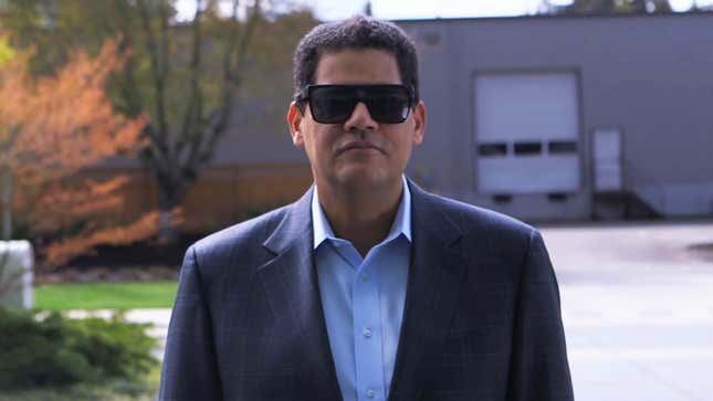 A screenshot of Reggie as he appeared in a Mega 64 E3 video, wearing sunglasses and a blue suit. 