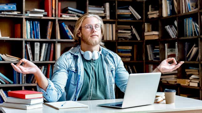 man studying at a desk, closing eyes to meditate in silence
