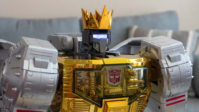 A close-up of Robosen and Hasbro's Transformers Grimlock Auto-Converting Robot Flagship Collector’s Edition's head in robot mode wearing an included golden crown accessory.