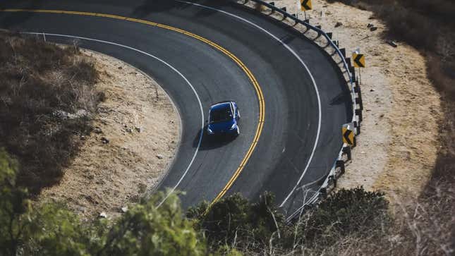 A Model 3 driving down a curving road. 