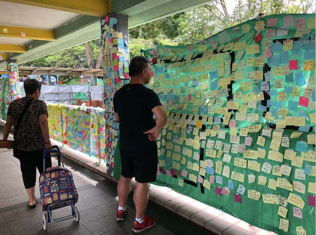 Passers-by read notes left by people at a Lennon Wall in Fanling, a northern suburb of Hong Kong.
