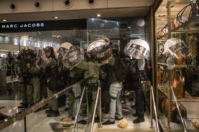 Riot police shelter against a wall as protesters throw objects at them after they chased protesters through a shopping mall on July 14, 2019 in Hong Kong.