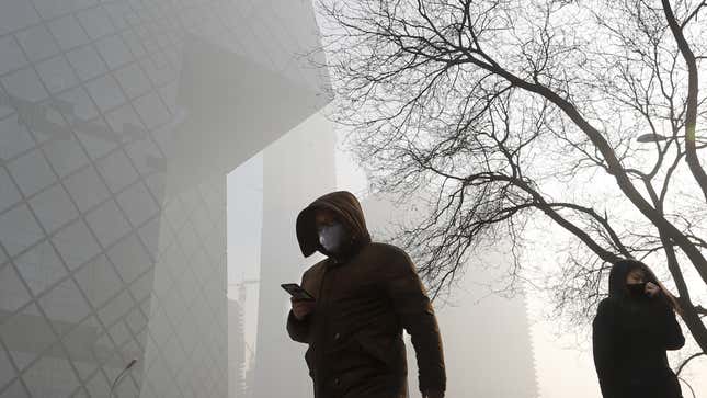 People wearing protection masks walk near the iconic headquarters of China's state broadcaster Central China Television (CCTV) at the Central Business District in Beijing as the capital of China is blanked by heavy smog on Tuesday, Jan. 3, 2017. China's Ministry of Environment says an unspecified number of companies have violated measures meant to reduce smog as the country deals with a phase of particularly noxious pollution. Beijing has been on "orange alert" the second highest pollution alert level since Friday. The alert was originally due to end on Sunday but authorities have extended it a further three days. (AP Photo/Andy Wong)