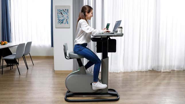 A person sitting on the Acer eKinekt BD 3 desk bike while also typing on a laptop computer.
