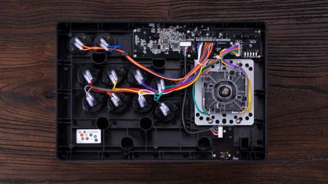 The black version of the 8BitDo Wireless Arcade Stick for Xbox flipped over and the rear panel removed revealing the swappable components inside.