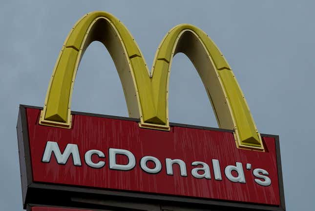 A view of the McDonald's golden arches sign wet with rain, set against a gray sky.