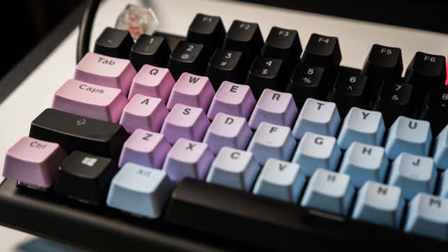 A photo of a dirty mechanical keyboard with pink, purple, and blue keycaps