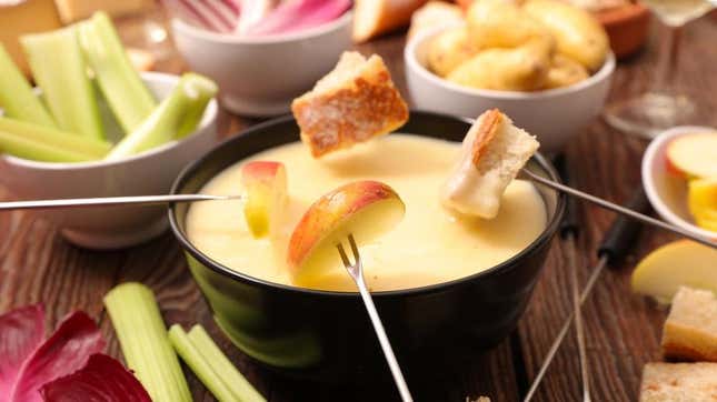 cheese fondue with apple slice being dipped in