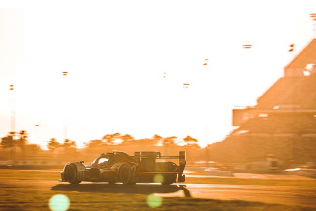 Rear view of the Porsche 963 car as it drives on the track at Daytona during the "Golden Hour."