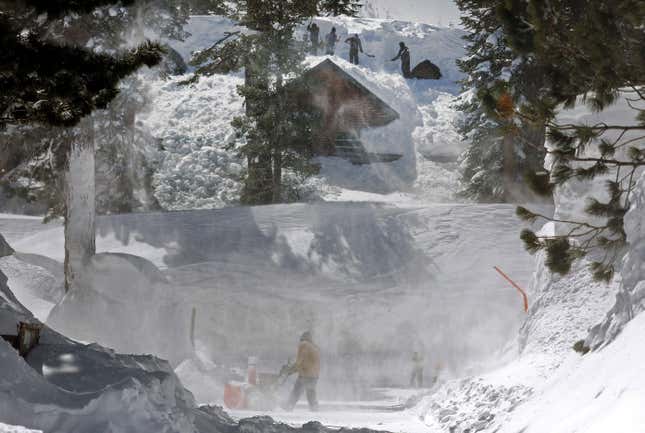 People work to clear snow off roofs and roads in Mammoth Lakes, CA.
