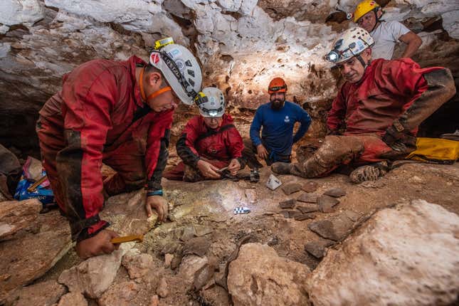 Explorers look at chunks of pottery on the floor.