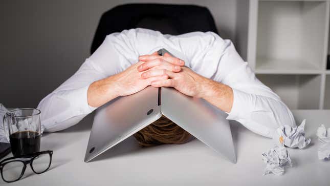 A man in a white collar shirt with a laptop tented over his head. 
