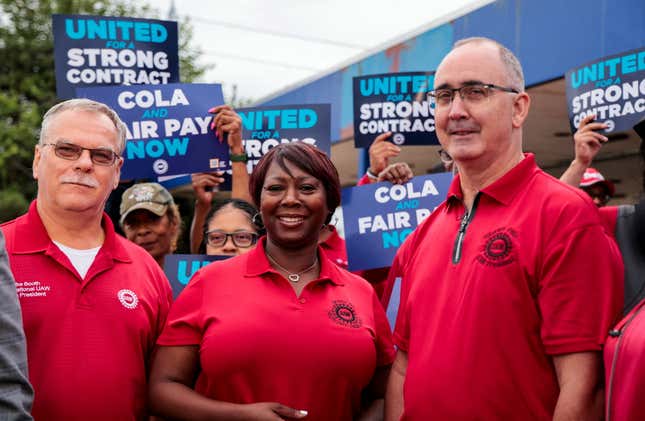 A photo of UAW union members outside a plant, holding signs that read "united for a strong contract" and "COLA and fair pay now."