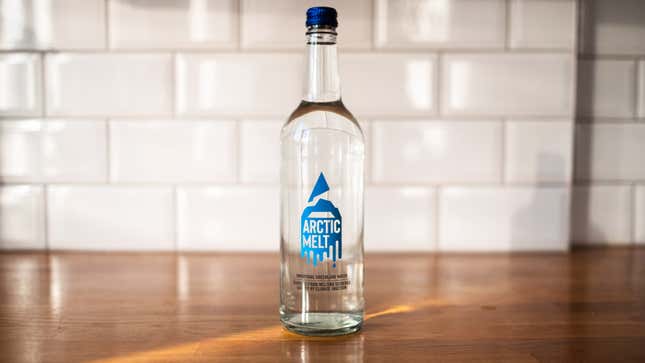 A glass bottle of Arctic Melt water on a countertop as a ray of light touches the bottle's base.