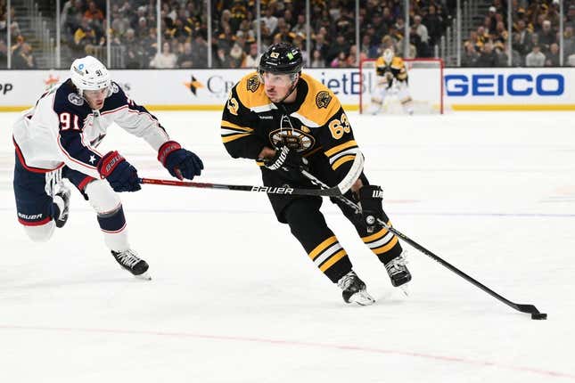 Mar 30, 2023; Boston, Massachusetts, USA; Boston Bruins left wing Brad Marchand (63) skates with the puck against Columbus Blue Jackets center Kent Johnson (91) during the third period at the TD Garden.