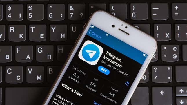 An iPhone with the app store open displaying the Telegram Messenger app sitting on top of a keyboard