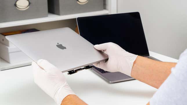 Person holding Mac laptop with gloves.