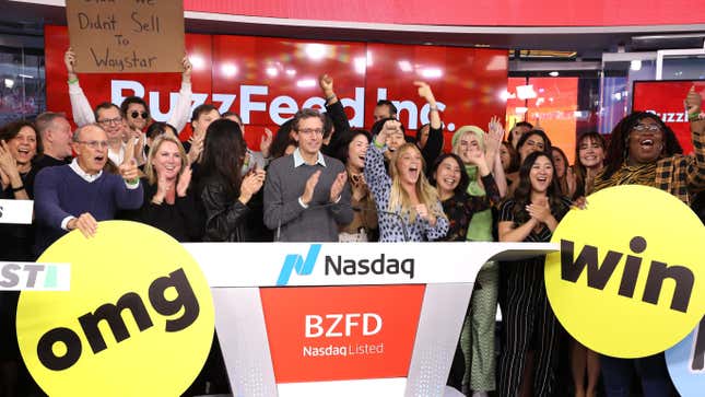 A crowd of people clap and cheer in front of a sign for BuzzFeed Inc.