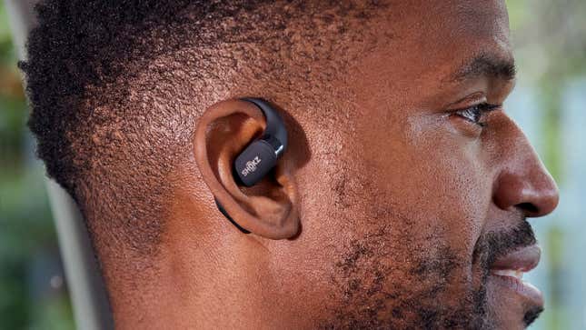 A person wearing the black colorway version of the Shokz OpenFit wireless earbuds.