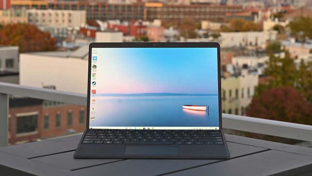 Imagen de una tableta Microsoft Surface Pro X sobre la mesa de una terraza, con una ciudad al fondo.