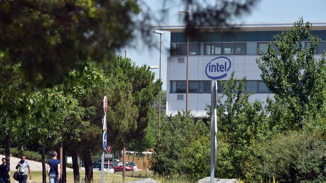 A building with the Intel logo on the far side of a small lawn past a few short trees.