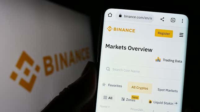 Person holding mobile phone with website of crypto exchange company Binance Holdings Ltd. on screen with logo.