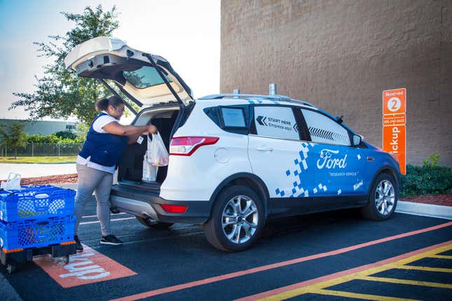 A Walmart employee loading groceries into a Ford test vehicle.