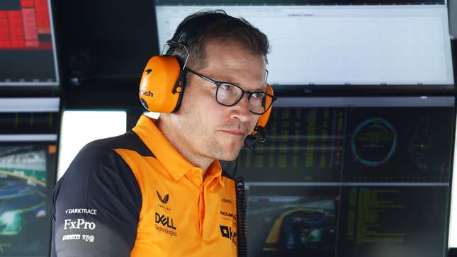 Andreas Seidl sitting on the pit-wall wearing a McLaren team polo and branded headphones.
