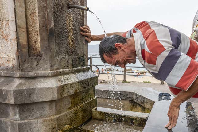 Un hombre se refresca en una fuente durante un caliente día de verano en Italia, el 11 de agosto de 2021.