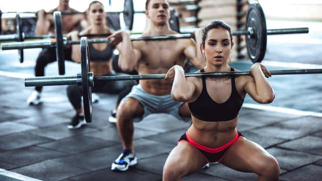 Photo of four white people, two women and two men, performing barbell cleans. 