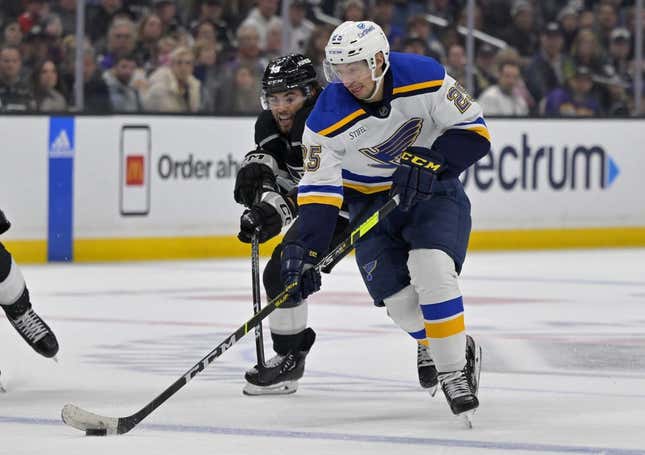 Mar 26, 2023; Los Angeles, California, USA; St. Louis Blues center Jordan Kyrou (25) and Los Angeles Kings left wing Alex Iafallo (19) battle for the puck in the third period at Crypto.com Arena.