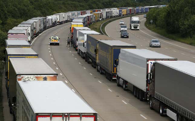 A police vehicle drives past lorries are backed up on the M20 motorway which leads from London to the Channel Tunnel terminal at Ashford and the Ferry Terminal at Dover, June 23, 2015.