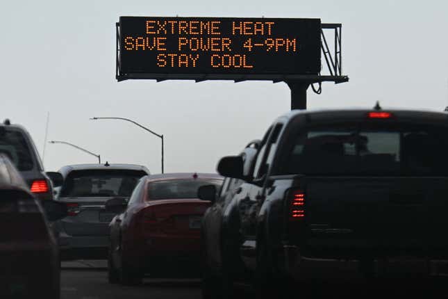 Vehicles drive past a sign on the 110 Freeway warning of extreme heat and urging energy conservation during a heat wave in downtown Los Angeles, California on September 2, 2022. 